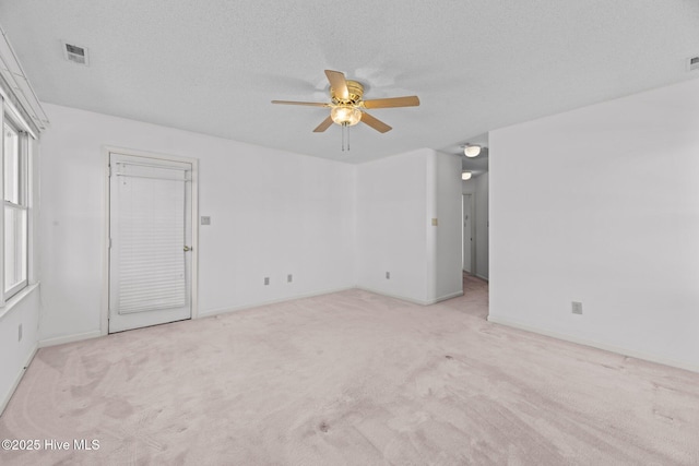 empty room with ceiling fan, light colored carpet, and a textured ceiling