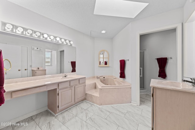 bathroom with vanity, a tub, a textured ceiling, and a skylight