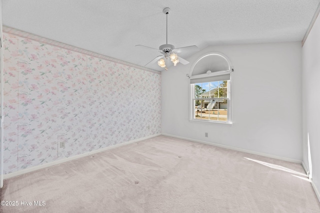 spare room featuring lofted ceiling, ceiling fan, light colored carpet, and a textured ceiling