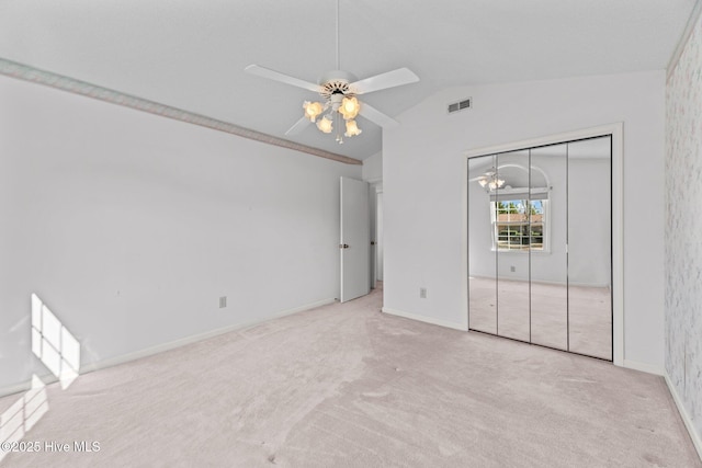 unfurnished bedroom with vaulted ceiling, light colored carpet, ceiling fan, and a closet