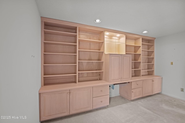 unfurnished office featuring built in desk and light colored carpet