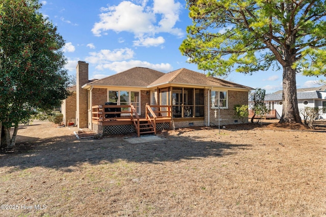 back of property with a wooden deck, a sunroom, and a yard