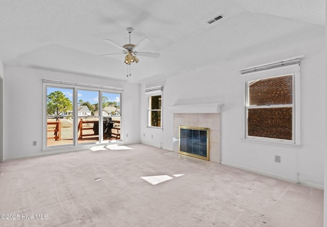 unfurnished living room featuring ceiling fan, light colored carpet, a fireplace, and a textured ceiling