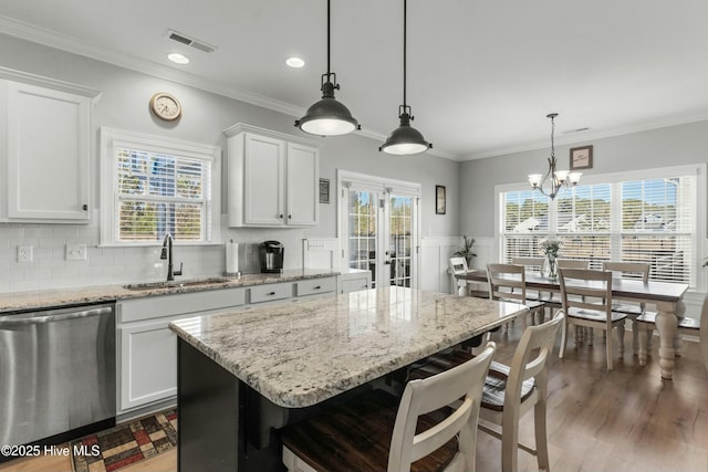 kitchen with sink, white cabinetry, hanging light fixtures, a kitchen island, and stainless steel dishwasher