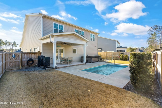 back of property with ceiling fan, a yard, a hot tub, and a patio area