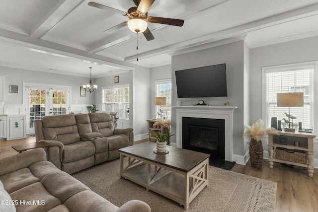 living room featuring beamed ceiling, wood-type flooring, ornamental molding, and ceiling fan with notable chandelier