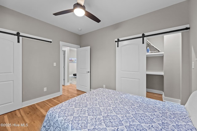 bedroom featuring hardwood / wood-style flooring, a barn door, and ceiling fan