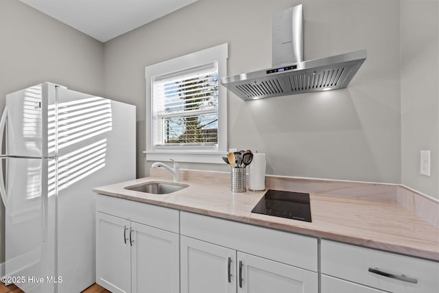 kitchen with sink, black electric stovetop, extractor fan, white cabinets, and white fridge