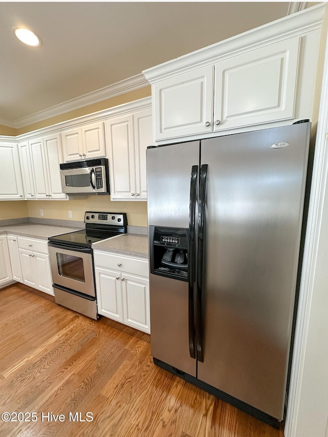 kitchen featuring white cabinetry, ornamental molding, light hardwood / wood-style flooring, and stainless steel appliances