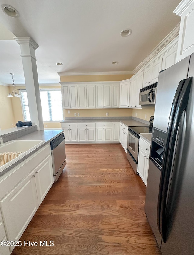 kitchen with sink, ornate columns, appliances with stainless steel finishes, dark hardwood / wood-style floors, and white cabinets