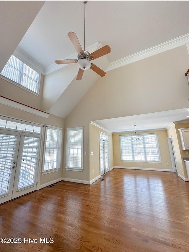 unfurnished living room featuring hardwood / wood-style flooring, ornamental molding, plenty of natural light, and high vaulted ceiling