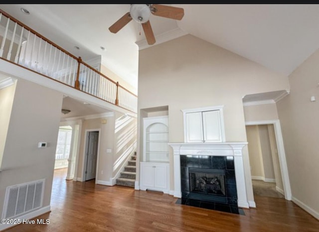 unfurnished living room with a tiled fireplace, dark wood-type flooring, and ornamental molding