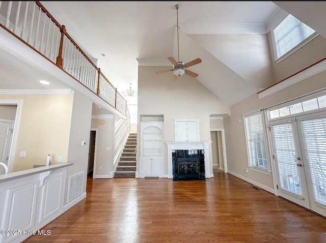 unfurnished living room featuring ceiling fan, high vaulted ceiling, a fireplace, wood-type flooring, and french doors