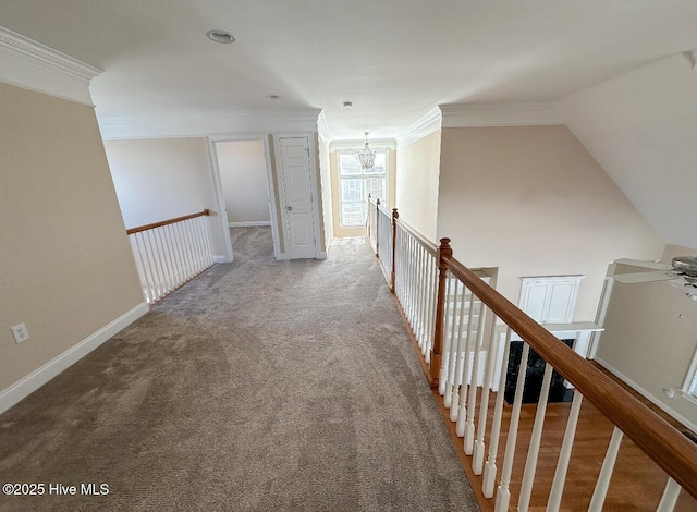 hall featuring crown molding, carpet flooring, and an inviting chandelier