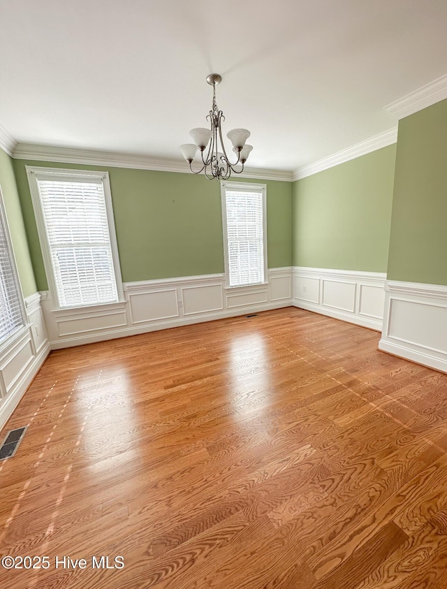 unfurnished room with ornamental molding, a chandelier, and light hardwood / wood-style flooring