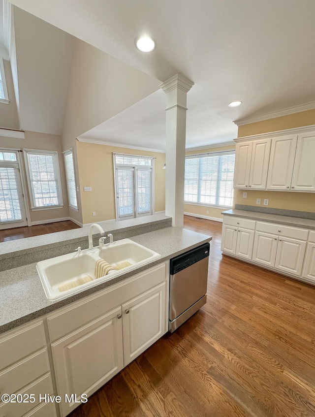 kitchen with sink, light hardwood / wood-style flooring, dishwasher, decorative columns, and white cabinets