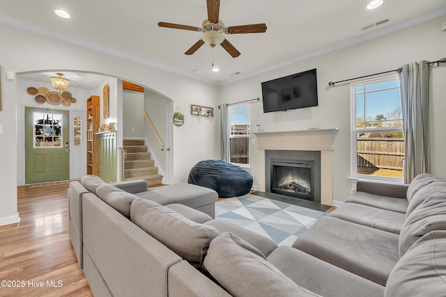 living room featuring crown molding, light hardwood / wood-style floors, and ceiling fan