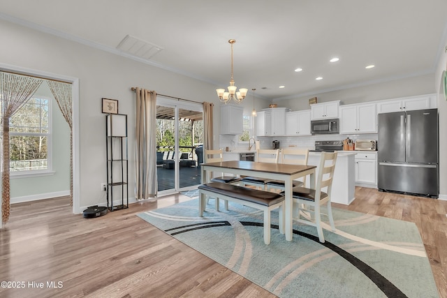 dining space with ornamental molding, a notable chandelier, and light wood-type flooring