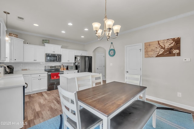 dining room with ornamental molding, sink, a notable chandelier, and light wood-type flooring