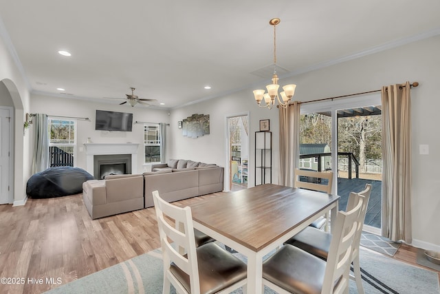 dining room with ornamental molding, ceiling fan with notable chandelier, and light hardwood / wood-style flooring