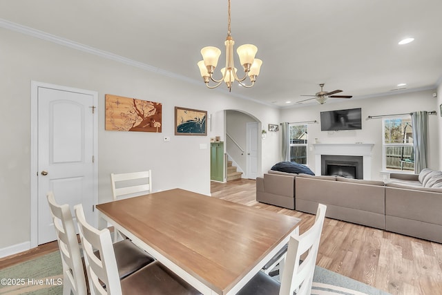 dining space with ornamental molding, ceiling fan with notable chandelier, and light hardwood / wood-style floors