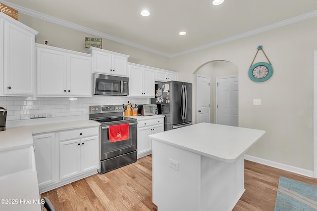 kitchen featuring a kitchen island, appliances with stainless steel finishes, white cabinets, backsplash, and light hardwood / wood-style flooring