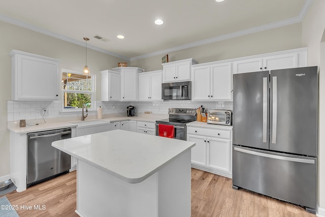 kitchen with stainless steel appliances, white cabinetry, a kitchen island, and sink