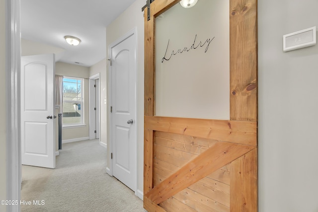 corridor featuring a barn door and light carpet