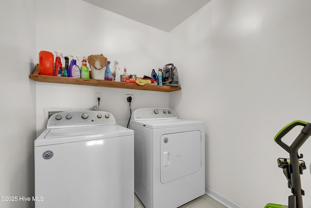 clothes washing area featuring light tile patterned flooring and washer and dryer