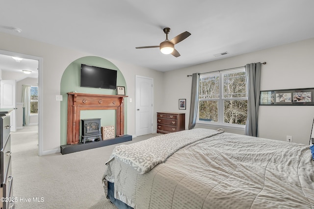 bedroom with ceiling fan, carpet, and a wood stove