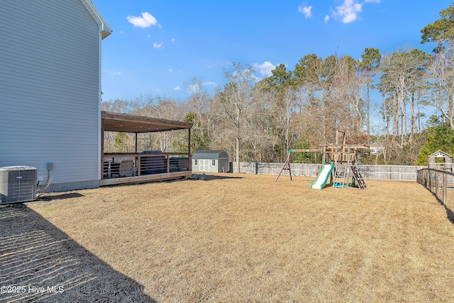 view of yard featuring central AC unit, a playground, and a storage unit