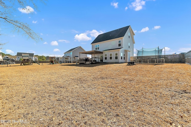 rear view of property with a playground, a trampoline, and a lawn