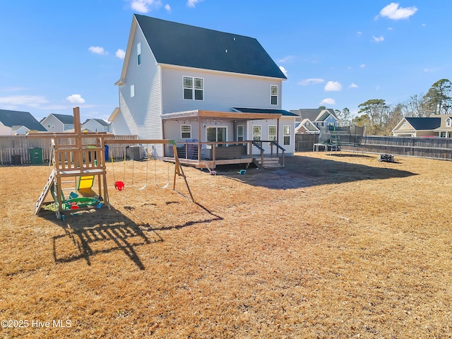 rear view of house featuring a playground, a deck, and a trampoline