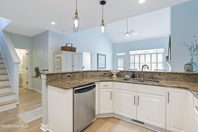 kitchen with sink, white cabinets, dark stone counters, hanging light fixtures, and stainless steel dishwasher