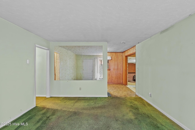 carpeted spare room with a textured ceiling and wood walls