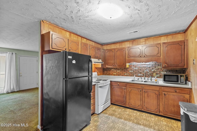 kitchen featuring sink, black refrigerator, white electric range oven, a textured ceiling, and light carpet