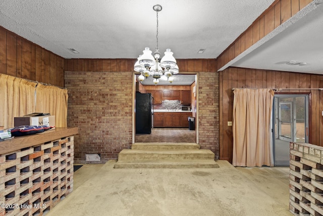 dining area with light colored carpet, wooden walls, a chandelier, and a textured ceiling