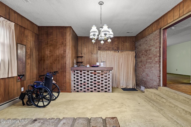 interior space featuring a notable chandelier, a textured ceiling, and wood walls