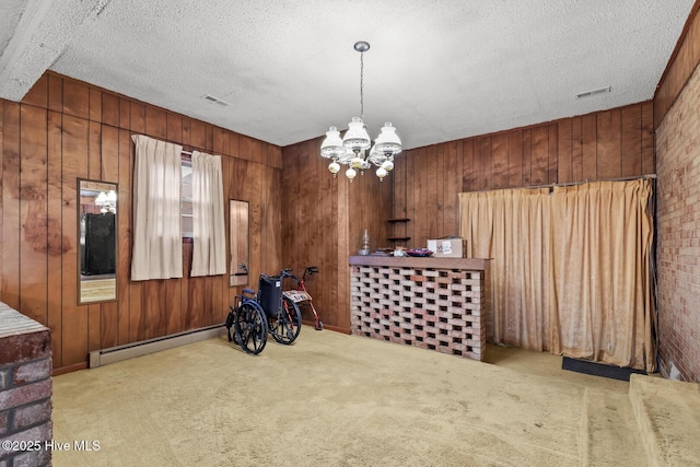 misc room with an inviting chandelier, wooden walls, a textured ceiling, and a baseboard heating unit