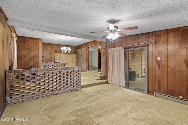 unfurnished room with a baseboard radiator, light colored carpet, a textured ceiling, and wood walls