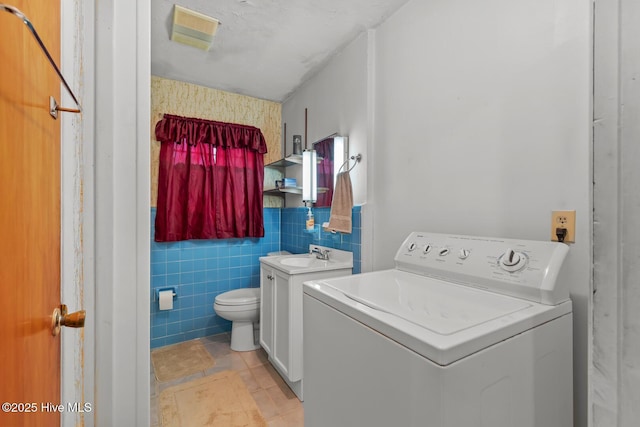 laundry area featuring tile walls, washer / clothes dryer, and sink