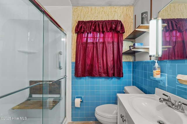 bathroom featuring a shower with door, vanity, tile walls, and toilet