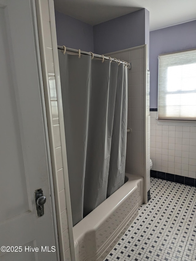 bathroom with tile patterned flooring, shower / tub combo, toilet, and tile walls