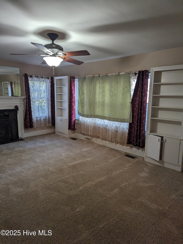 unfurnished living room featuring ceiling fan and carpet flooring