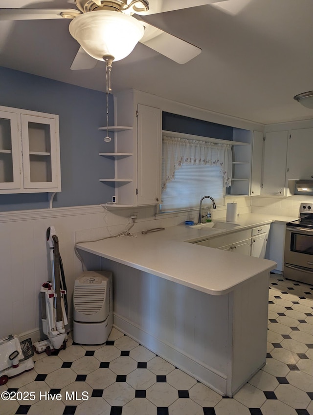 kitchen featuring kitchen peninsula, stainless steel electric range, and white cabinets