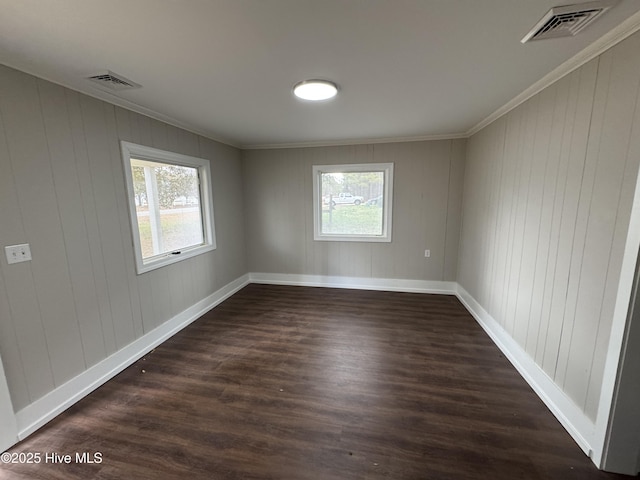 empty room with ornamental molding, a healthy amount of sunlight, dark hardwood / wood-style floors, and wood walls