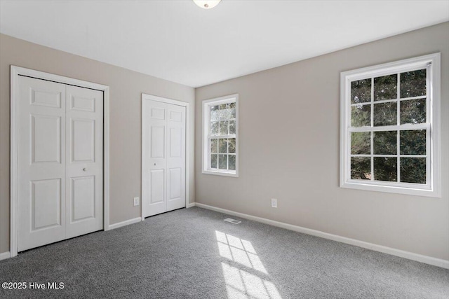 unfurnished bedroom featuring multiple closets and carpet