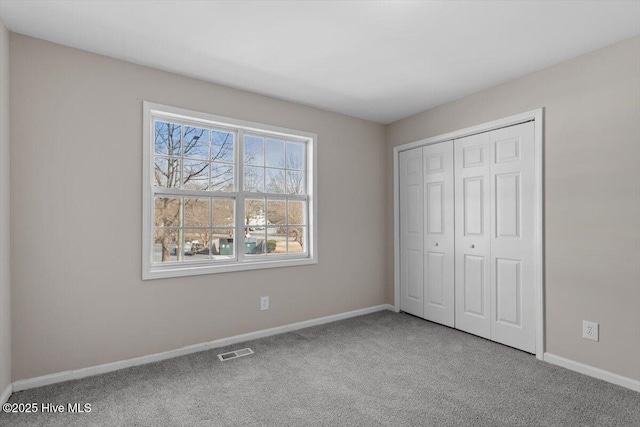 unfurnished bedroom featuring light colored carpet and a closet