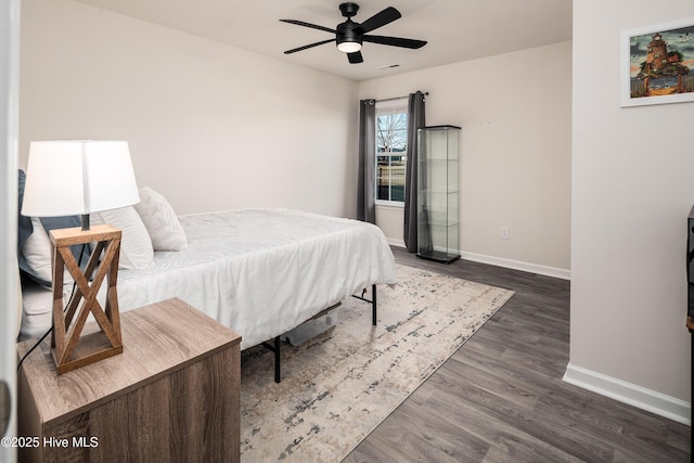 bedroom with dark hardwood / wood-style flooring and ceiling fan