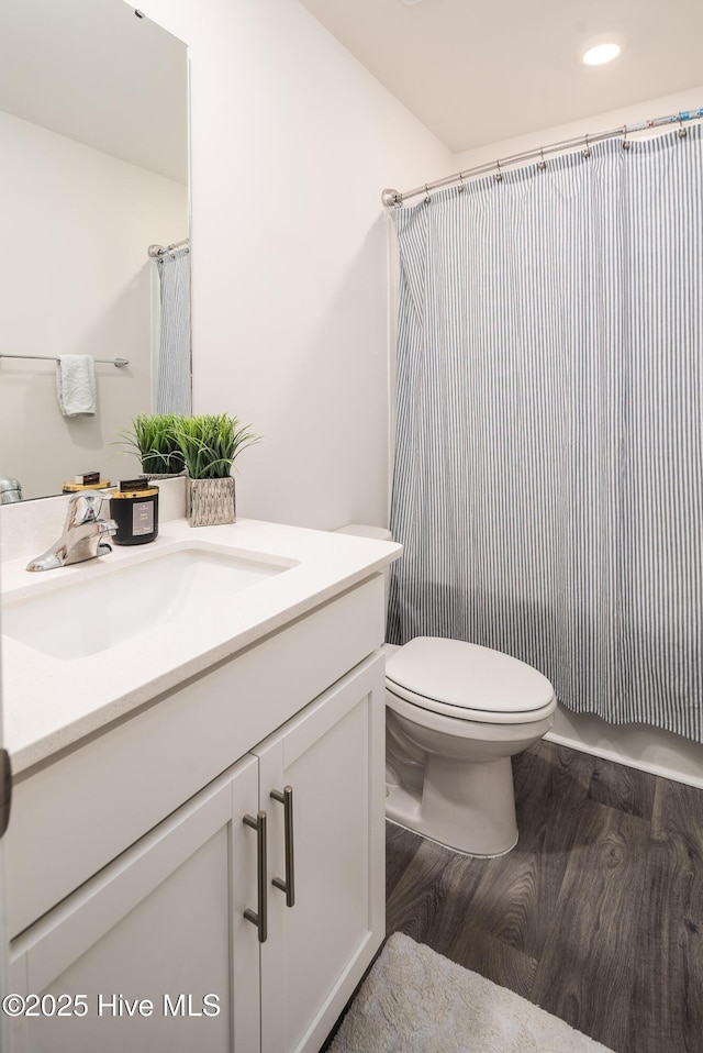 bathroom with hardwood / wood-style flooring, vanity, toilet, and walk in shower